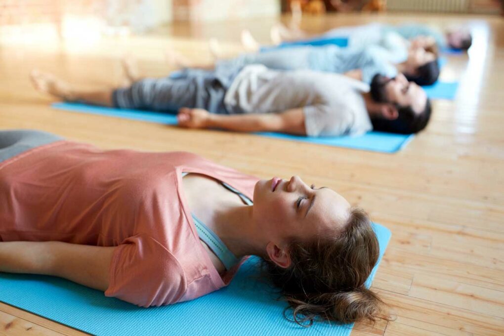 Gruppe liegt in der Yogastunde auf dem Boden und machen Shavasana